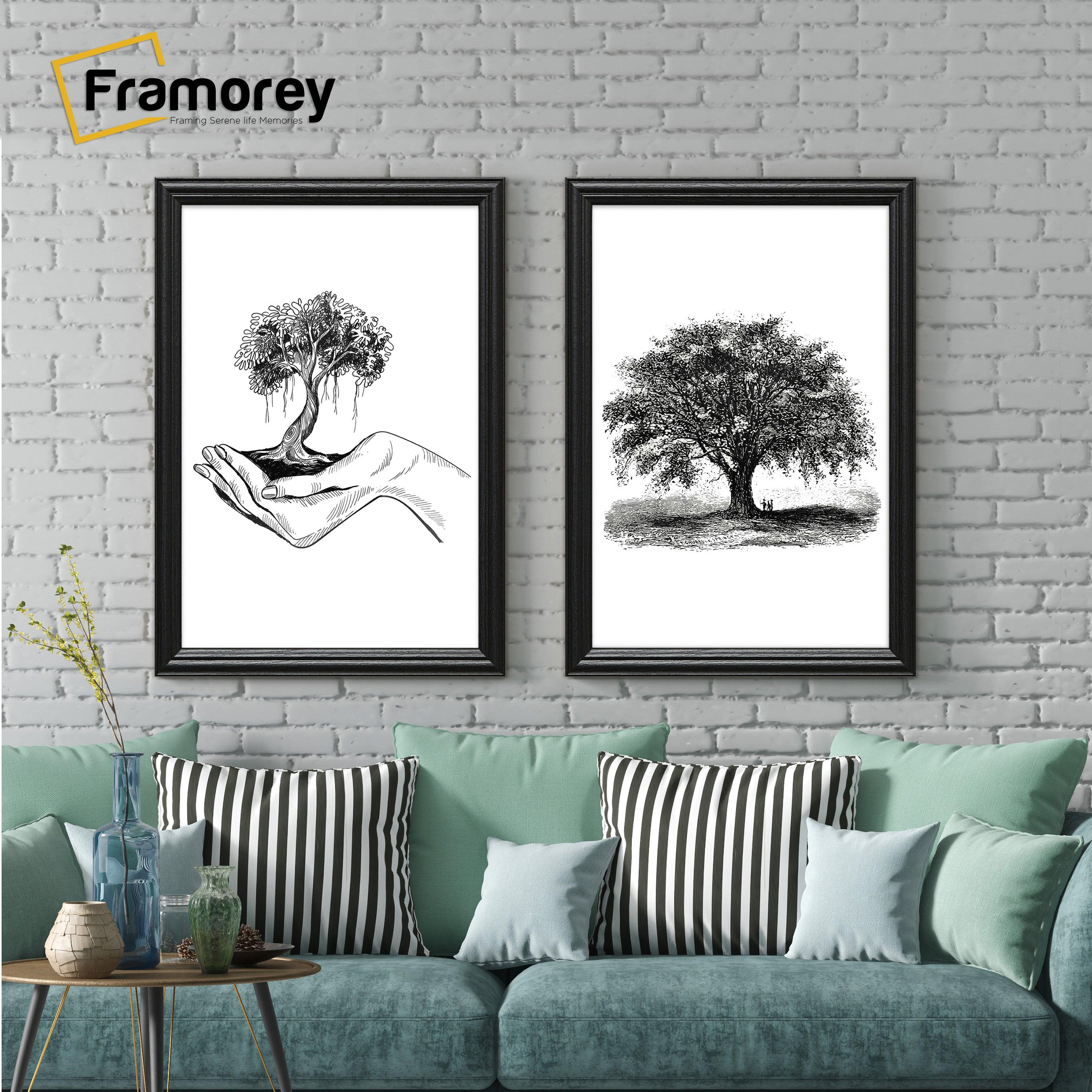 Two antique style black picture frames displaying black and white artwork hanging above a couch against a brick wall