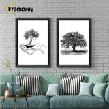 Two antique style black picture frames displaying black and white artwork hanging above a couch against a brick wall