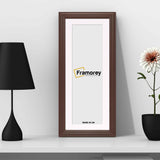 Antique Style Panoramic Size Mahogany Picture Frame Wall Art Picture with white Mount with a black lamp and a flower pot place around it.