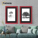 Two antique style red picture frames with black mounts displaying black and white artwork hanging above a couch against a brick wall