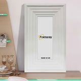 Big step style white wooden picture frame placed on a table.