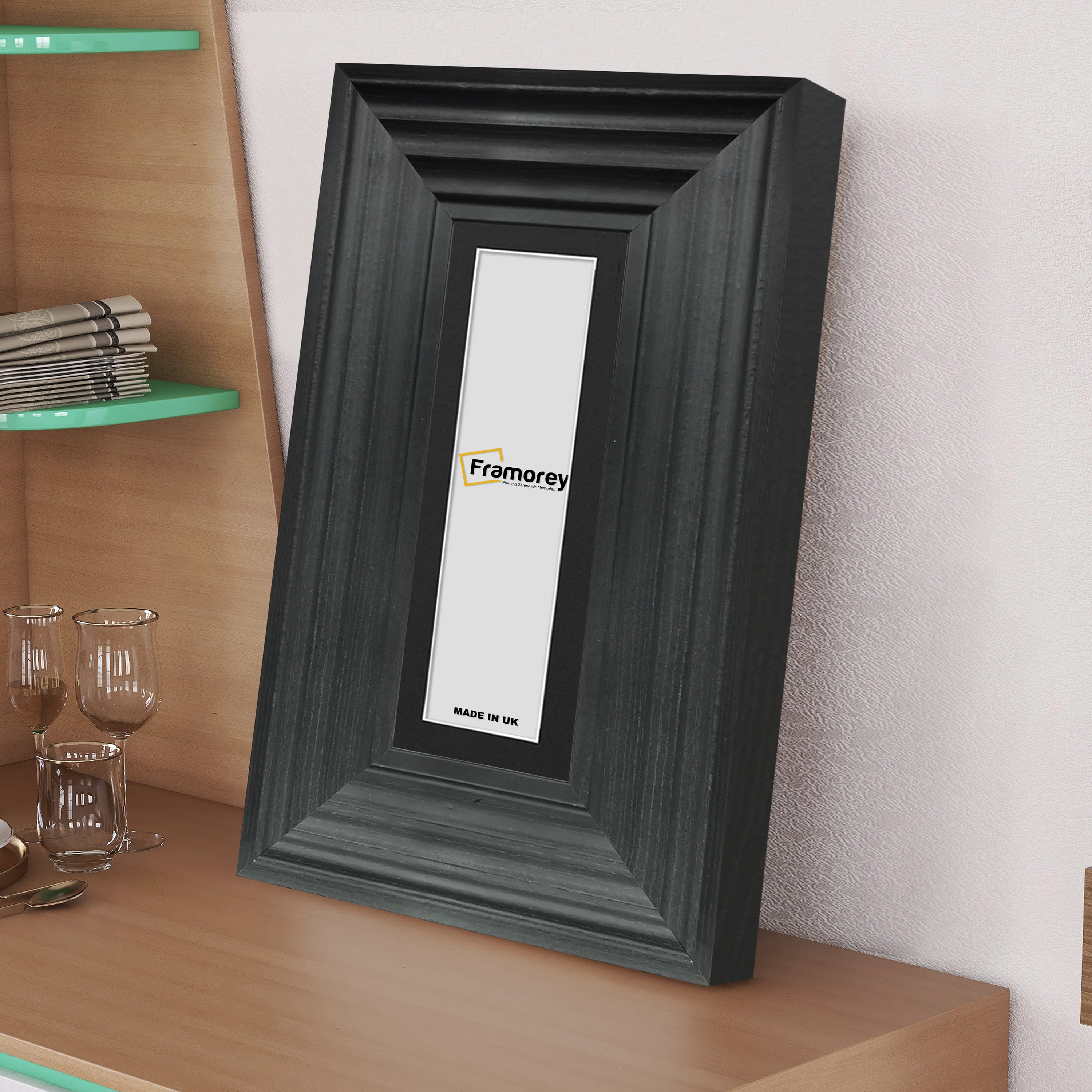 side view of a Panoramic Size Black Wooden Photo Frame Big Step With Black Mount on a wooden drawer leaning with the wall.