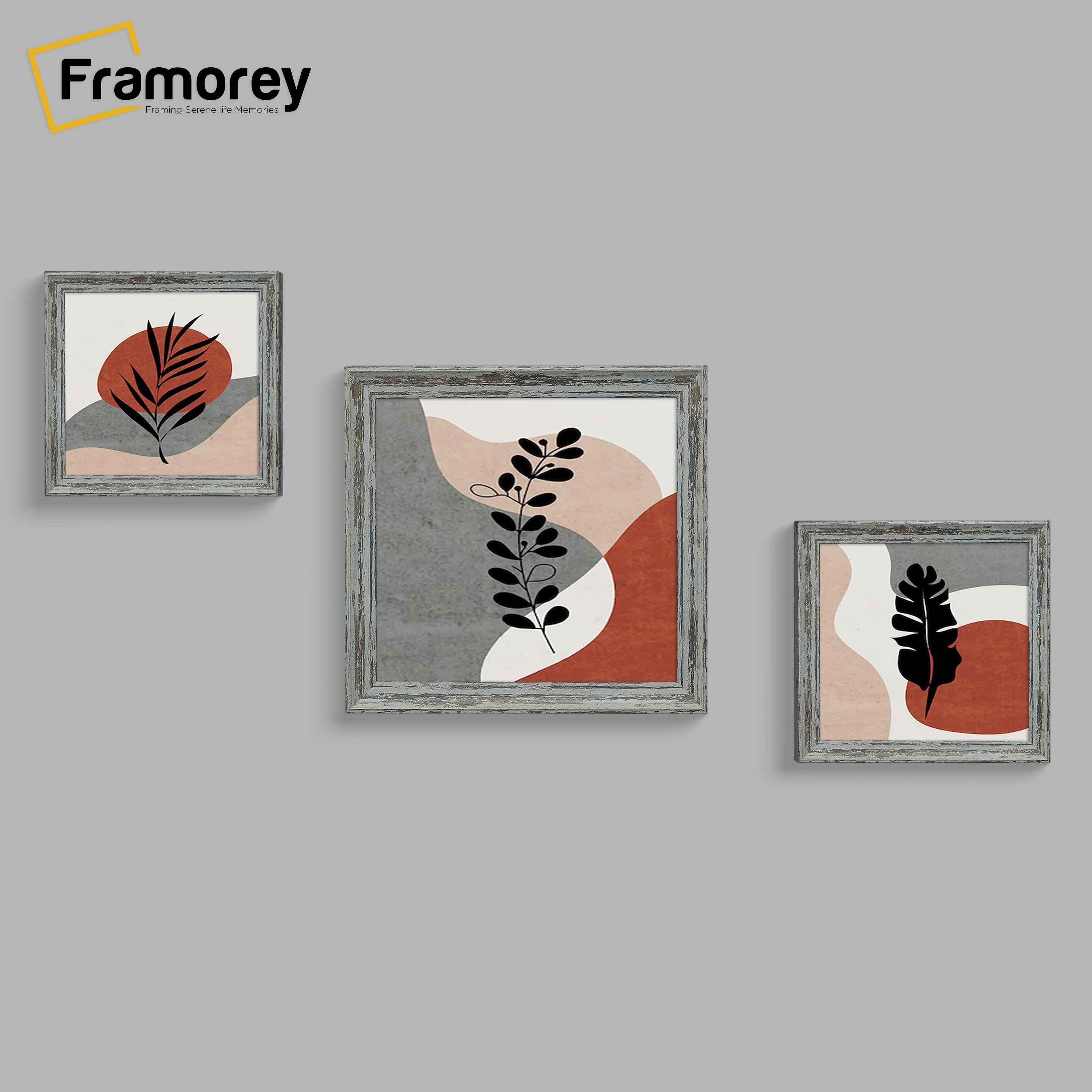 A set of three Picture Frame With abstract art prints featuring botanical elements in black, set against organic shapes in earthy tones of red, beige, and gray. 