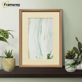 Oak Minimalist Poster Frame With Ivory Mount on a black wooden slab with some decorative items on its sides.