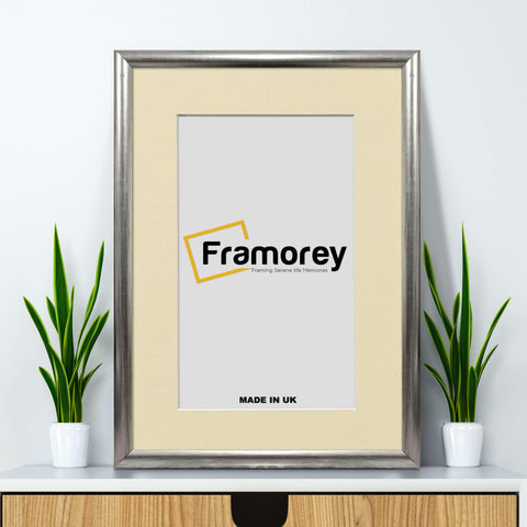 Rectangle silver picture frame with ivory mount placed on a wooden floor.