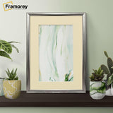 Rectangle silver poster frame with ivory mount on a wooden table with some decorative pots placed on its sides.