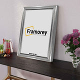 Side view of a Reverse Silver Poster Frame on a table leaning with the white wall.