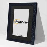 Side view of a Black Picture Frame Picture Frame Rockstar With Black Mount leaning with a wall on a white floor.