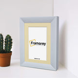 Side view of a Limed White Photo Frame With Ivory Mount standing on a white floor or surface.