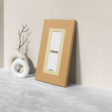 Side view of a Panoramic Oak Photo Print Frame with Ivory Mount is leaning with the wall on a flat wooden surface.