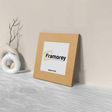 Side view of a Square Oak Home Decor Poster Frame Handmade Wooden Frame is leaning with the wall on a wooden surface.