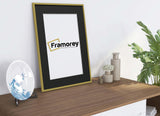 Side view of a Thin Gold Picture Frame With Black Mount with some details with a plate and some bottles placed around it.