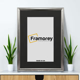 Silver Minimalist Picture Frame Wall Art Frame With Black Mount on a wooden drawer and a Framorey logo place inside it.