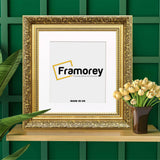 Square Photo Frame Dahlia Gold Poster Frame With White Mount on a wooden slab standing with a green check wall.
