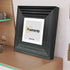 Side view of a Square Black Wooden Poster Frame Big Step Style with White Mount leaning with the wall.