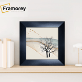 Square size Black picture frame placed on a table with some decorative things.