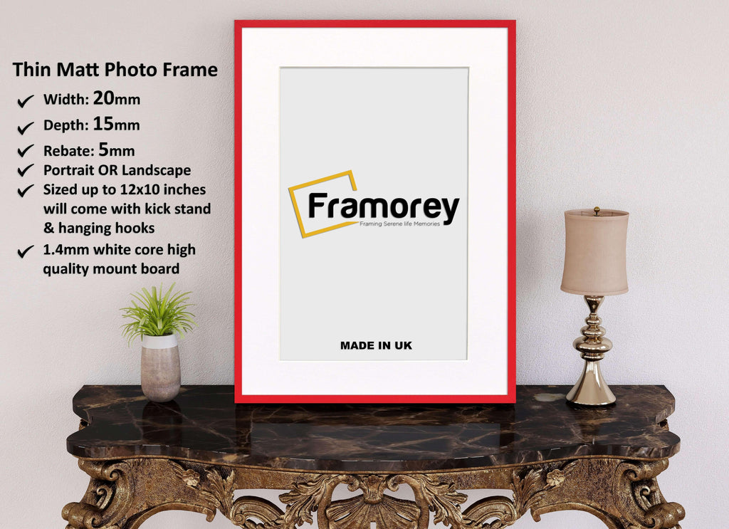 Thin Red Photo Frame With White Mount on a wooden table standing with the wall and some detail on its left.
