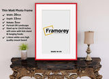 Thin Red Photo Frame With White Mount on a wooden table standing with the wall and some detail on its left.