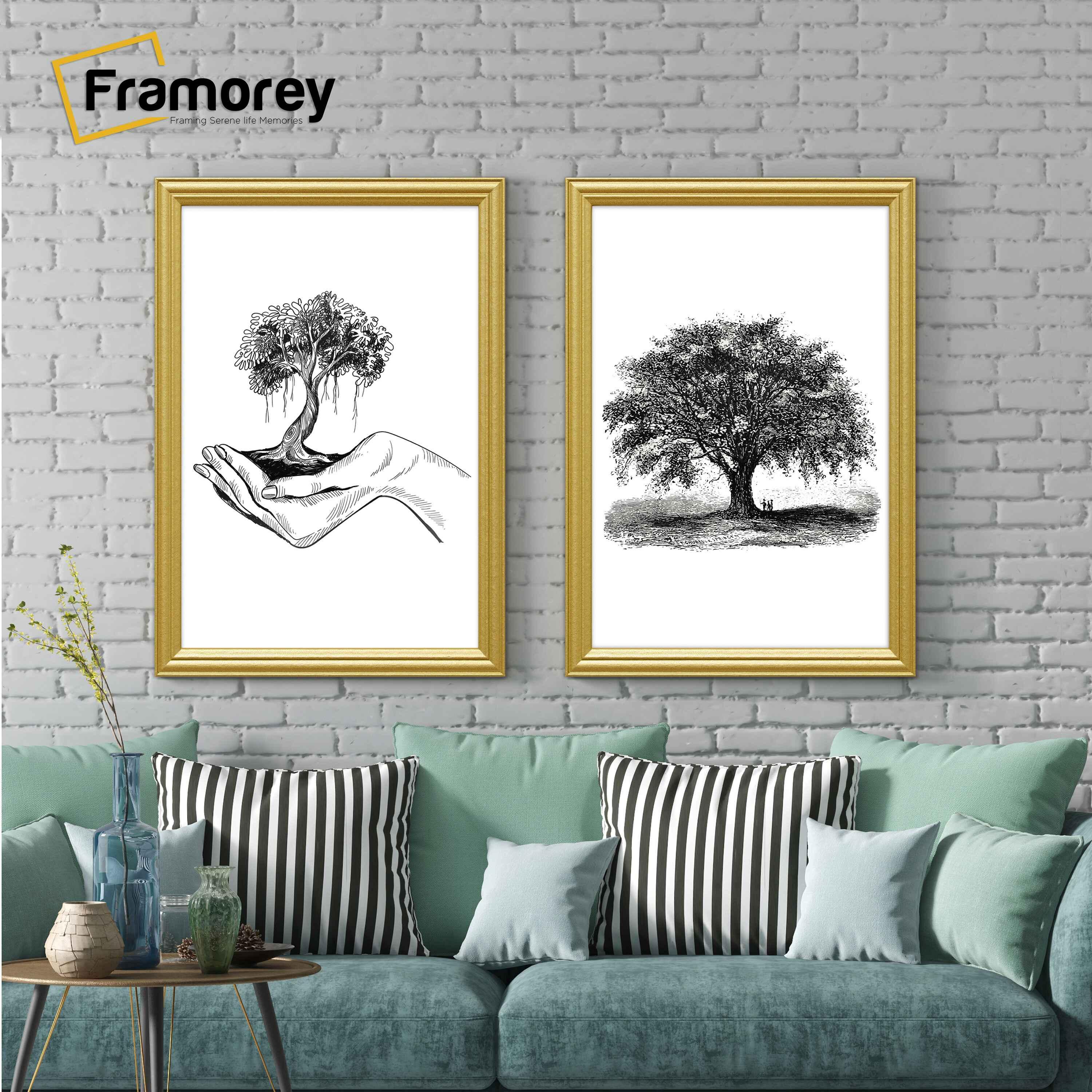 Two antique style gold picture frames  displaying black and white artwork hanging above a couch against a brick wall