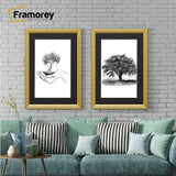 Two antique style gold picture frames with black mounts displaying black and white artwork hanging above a couch against a brick wall