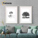 Two antique style white picture frames with white mounts displaying black and white artwork hanging above a couch against a brick wall