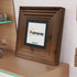 Big step style side view Walnut poster frame with black mount placed on a table.