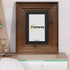 Walnut wooden picture frame with black mount placed on a table.