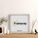 White Square Reverse Style Poster Frame on a floor with some decorative items.