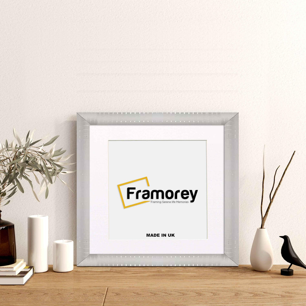 Silver Reverse Style poster frame with white mount with decorative things placed near it.