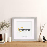 Silver Reverse Style poster frame with white mount with decorative things placed near it.
