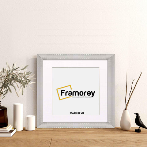 Silver Reverse Style poster frame with white mount with decorative things placed near it.